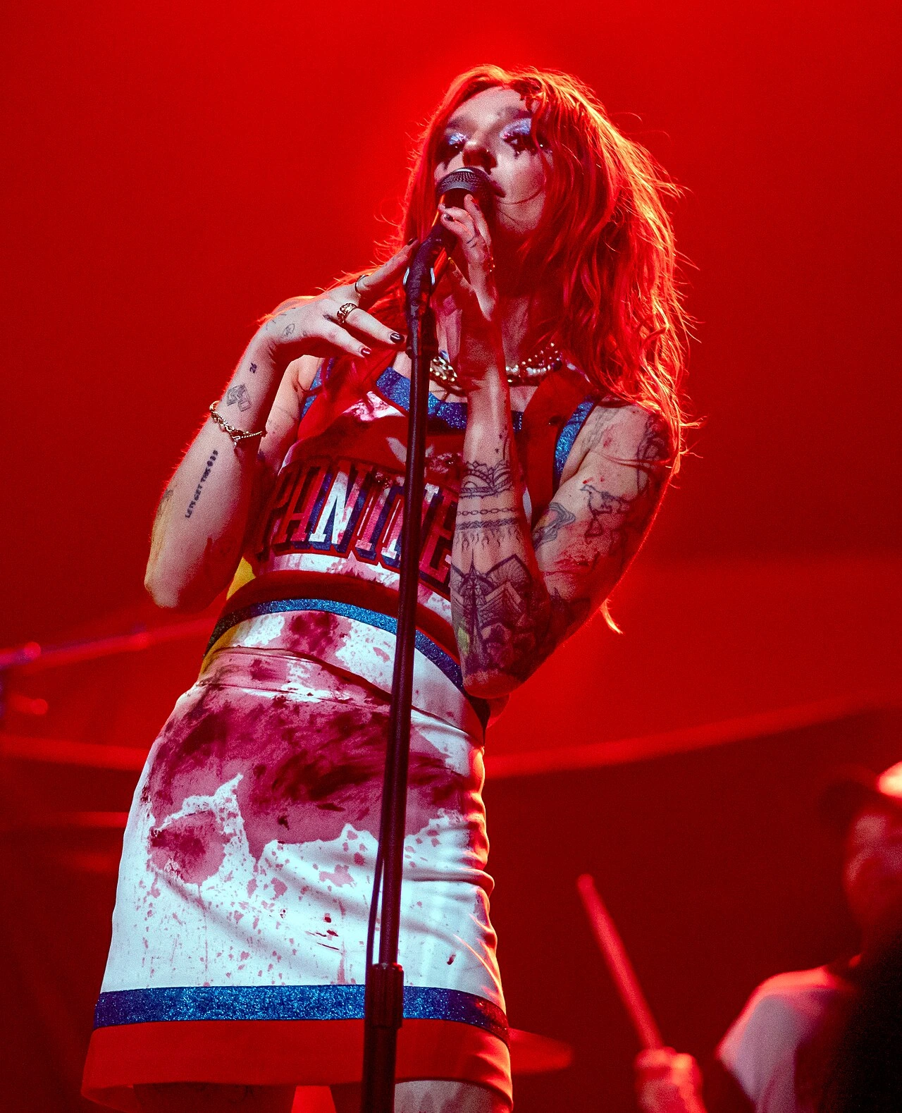 Royal & the Serpent performing onstage under red lighting, singing into a microphone.