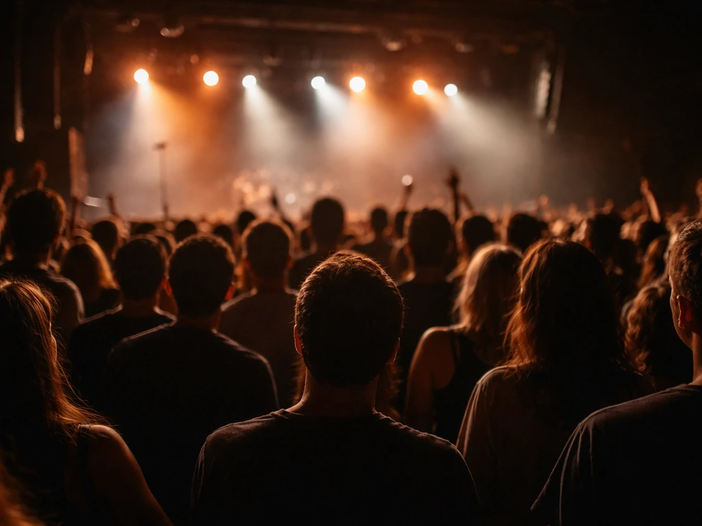 Rock concert audience in a dim venue, stage lights shining, emphasizing live touring energy.