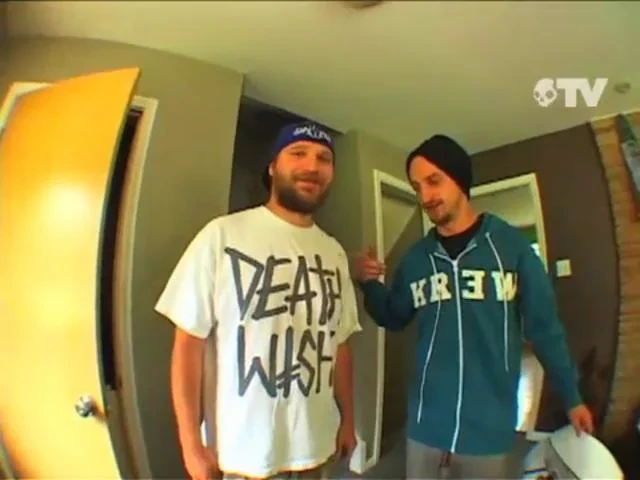 A real photo of Mike Plumb (Lizard King) standing indoors with another person, from a video frame.