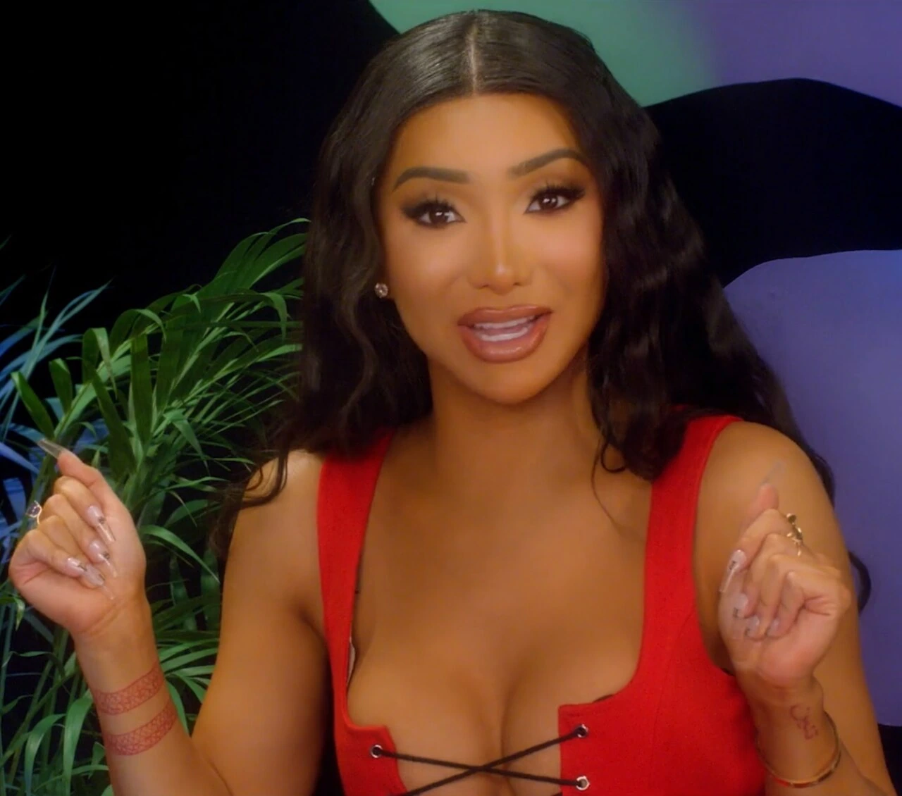 Nikita Dragun speaking in a red top during a video appearance.